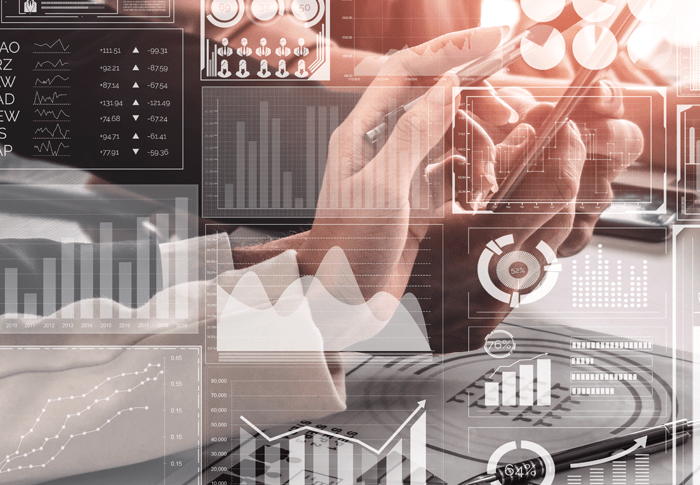 Overlay of graphs & charts with a hand holding pen pointing at tablet in background