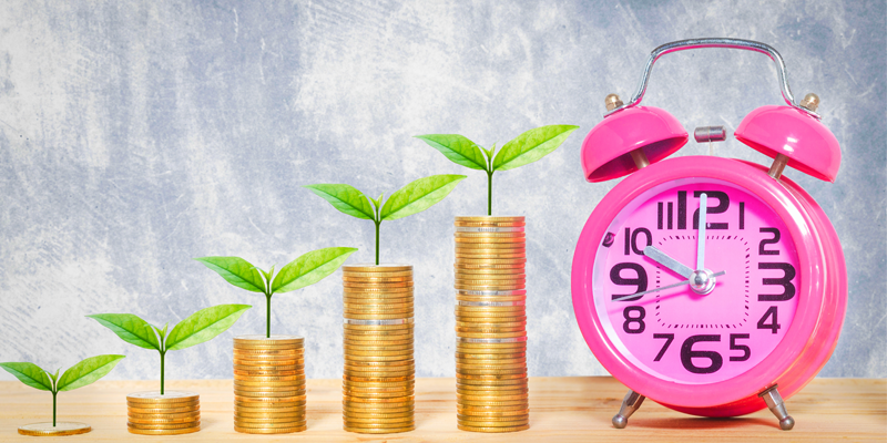increasing stacks of coins with green leaves growing out of top next to a pink alarm clock